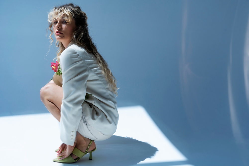 Sesión de fotografía de moda con la modelo sentada sobre un fondo azul