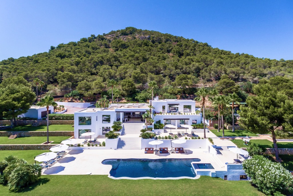 Vista aérea de una villa blanca con piscina rodeada de pinos